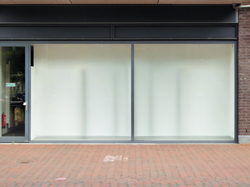 The shopfront window of a commercial retail space features large, frameless glass panels with a frosted appearance, providing privacy and a clean, modern look. The glass is free from smudges or dirt, 